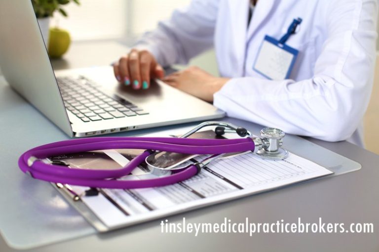 A healthcare professional, focused on strategies for building a successful medical practice, works on a laptop at their desk.