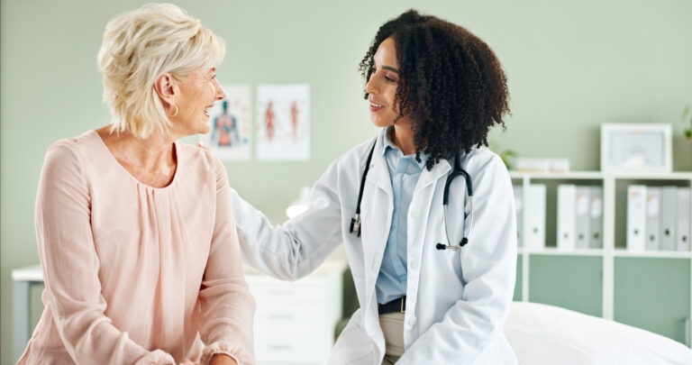 Female physician talking with older, female patient in an office exam room