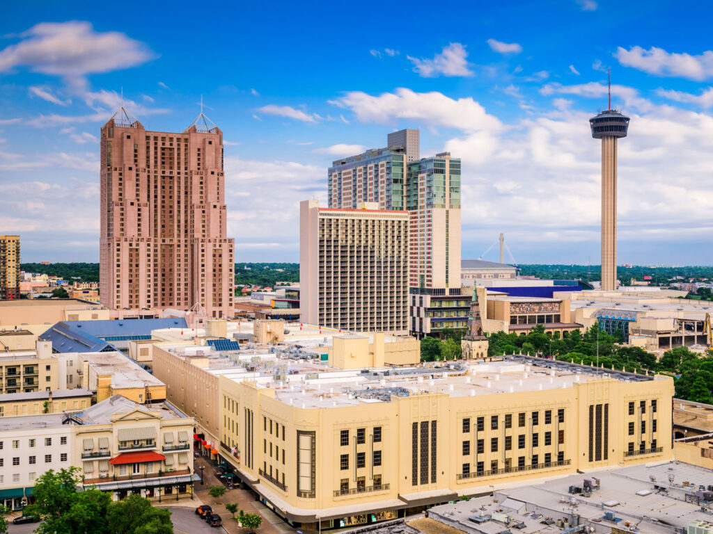 San Antonio skyline with Tower of the Americas, downtown buildings, and cityscape under a bright blue sky.